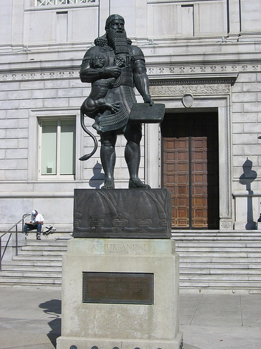 Ashurbanipal, holding a lion and a clay tablet.